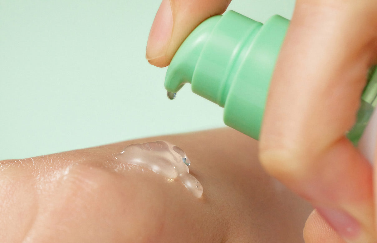 Person applying Purito Seoul's clear gel or lotion to their arm with a green applicator.
